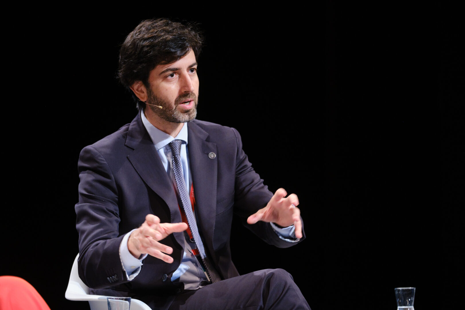 Hombre con traje gesticulando con las manos mientras habla durante una conferencia